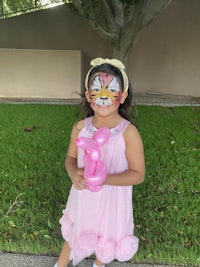 a little girl in a pink dress holding a pink balloon