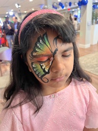 a little girl with a butterfly painted on her face